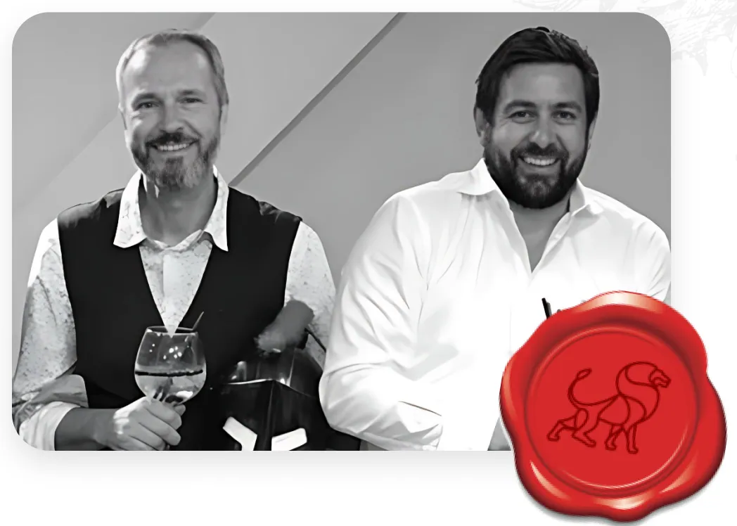 Smidgin's two founders photographed in black and white, one holding a gin glass, with the brand's red wax lion seal